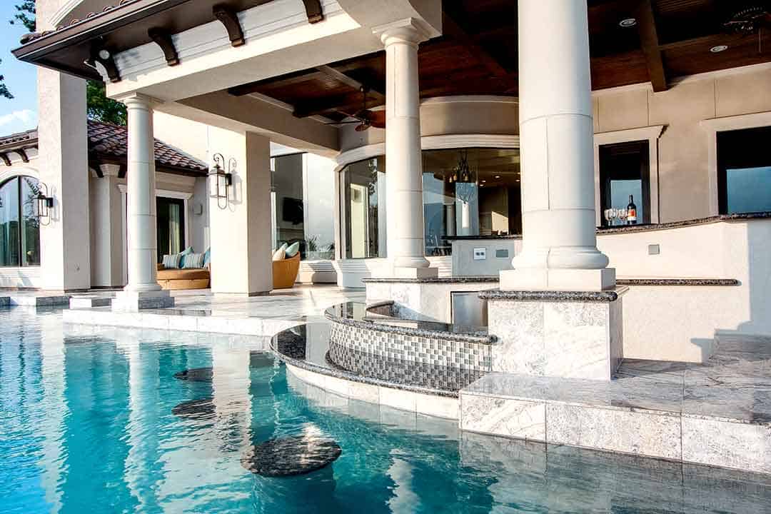 Poolside patio with outdoor kitchen and white columns in The Woodlands