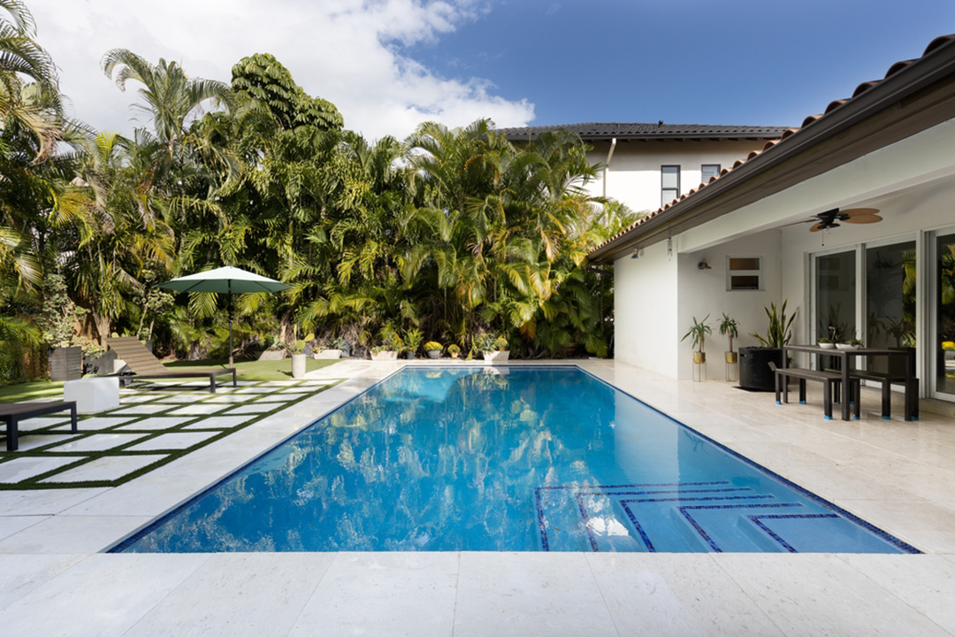 Modern backyard pool by Bellaire Pool Builder, surrounded by lush greenery and elegant patio design